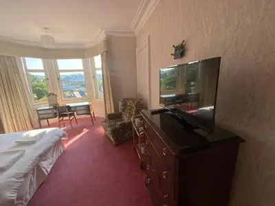 a hotel room with a bed and a flat screen tv at Dunrigh Guest House in Oban