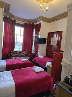 a hotel room with three beds and a television at The Residence - NO 57 in Edinburgh