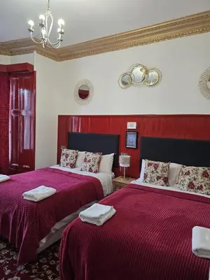 a bedroom with two beds with red sheets and a chandelier at The Residence - NO 57 in Edinburgh