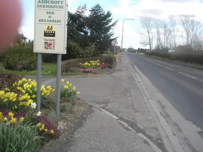 a sign on the side of a road with flowers at Ashcroft Farmhouse in East Calder
