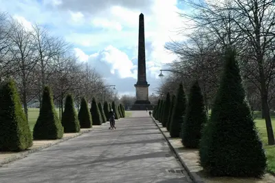 a person walking down a sidewalk in front of a obelisk at The Stables - Fabulous stylish flat in Merchant City & Free Secure Parking in Glasgow
