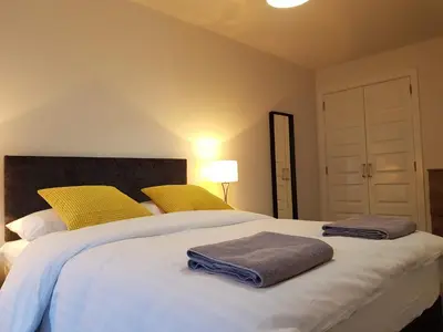 a bedroom with a large white bed with yellow pillows at 5 Royal View Apartments in Stirling