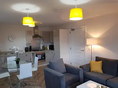 a living room with two couches and a table and a kitchen at 9 Royal View Apartment in Stirling