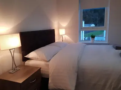 a bedroom with a large white bed and a window at 11 Royal View Apartments in Stirling