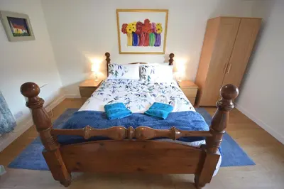 a bedroom with a wooden bed with blue pillows at Byron Cottage overlooking Loch Goil in Lochgoilhead