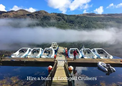 a group of boats parked at a dock on a lake at Byron Cottage overlooking Loch Goil in Lochgoilhead