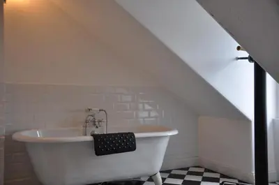 a white bath tub in a bathroom under a stairs at Kames Hotel in Tighnabruaich