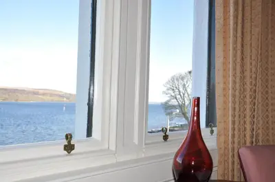 a red vase sitting in front of a window at Kames Hotel in Tighnabruaich