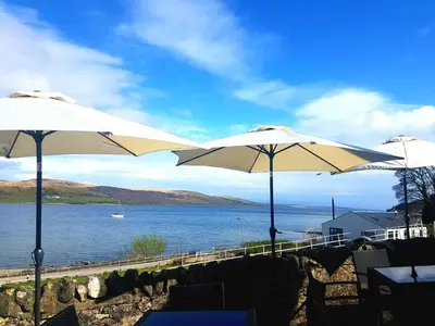 two white umbrellas sitting next to a body of water at Kames Hotel in Tighnabruaich