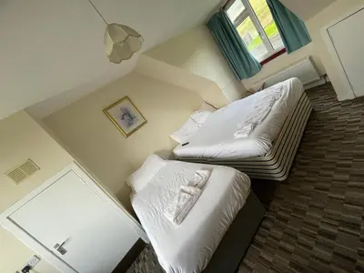 a small room with two beds and a window at Lochway Hotel in Dumbarton
