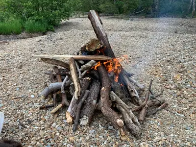 a pile of logs and a fire on the ground at Ben Lomond Lodge in Rowardennan