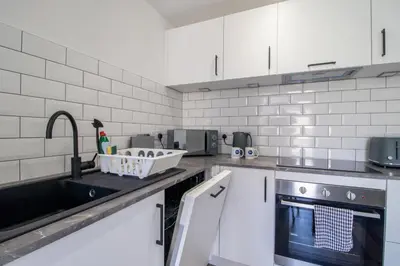 a kitchen with white cabinets and a sink at Abbey House in Paisley