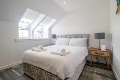 a bedroom with a large white bed with two towels on it at Abbey House in Paisley