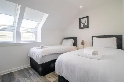 two beds in a room with two windows at Abbey House in Paisley