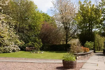 a garden with benches and flowers and trees at Bankton Rooms & Lodges in Livingston