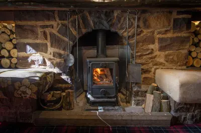 a stone fireplace in a room with a stove at Bankton Rooms & Lodges in Livingston