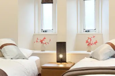 two beds in a room with two windows at Edinburgh Church Apartments in Edinburgh