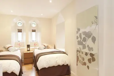 two beds in a small room with two windows at Edinburgh Church Apartments in Edinburgh
