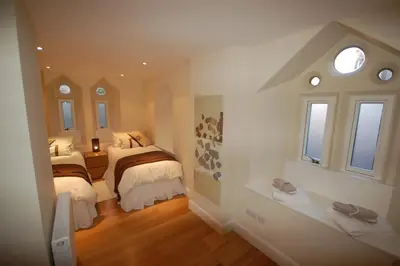 a small bedroom with two beds and two windows at Edinburgh Church Apartments in Edinburgh