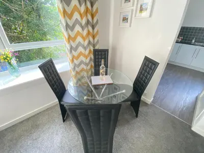a glass table with two chairs and a window at Paisley Central Apartment #4 in Paisley