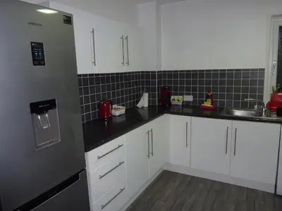 a kitchen with white cabinets and black counter tops at Paisley Central Apartment #4 in Paisley