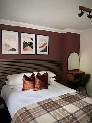 a bedroom with a bed with three pictures on the wall at Lochside Guest House in Arrochar