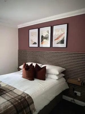 a bedroom with a bed with three pictures on the wall at Lochside Guest House in Arrochar
