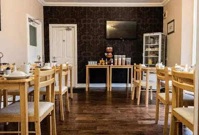a dining room with tables and chairs and a television at Lochside Guest House in Arrochar