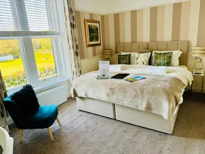a bedroom with a large bed and a chair at Buchan Guest House in Moffat
