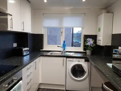 a kitchen with a washing machine in a sink at Carnegie Place in East Kilbride