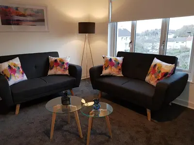 a living room with two couches and two tables at Carnegie Place in East Kilbride