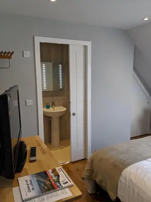 a bedroom with a bed and a bathroom with a sink at Falcon Crest Guest House in Edinburgh