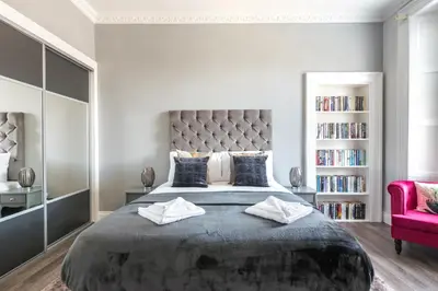 a bedroom with a large bed and a red chair at Spacious newly refurbished central apt in Edinburgh