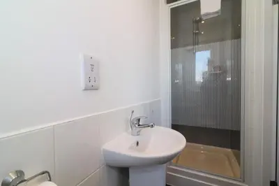 a white bathroom with a sink and a shower at Signature- Connelly House in Motherwell