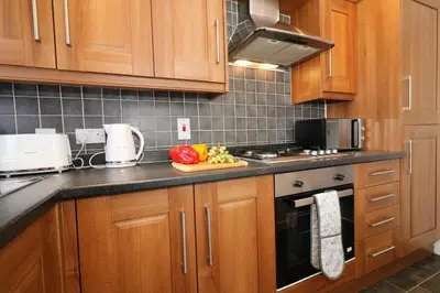 a kitchen with wooden cabinets and a cutting board of fruit on the counter at Signature- Connelly House in Motherwell