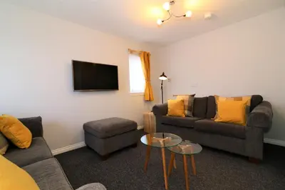 a living room with two couches and a tv at Signature- Connelly House in Motherwell