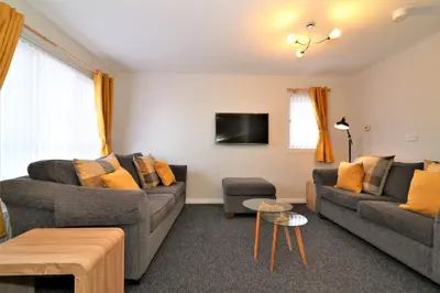 a living room with two couches and a tv at Signature- Connelly House in Motherwell