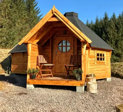 a log cabin with two chairs and a table at The Nest Glamping Pod in Dalmally