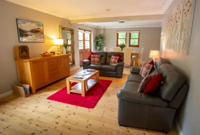 a living room with a couch and a table at Bonnie Banks Cottage in Balloch