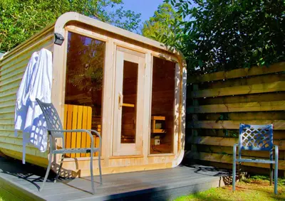 a cabin with a door and two chairs on a deck at Bonnie Banks Cottage in Balloch