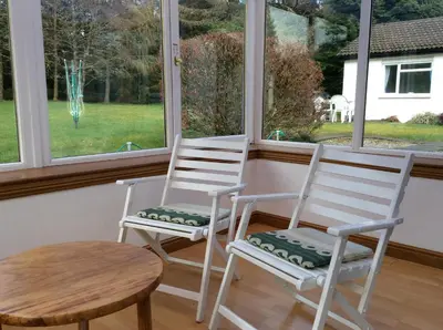 two white chairs and a table in front of a window at Dalkell Cottages in Tyndrum