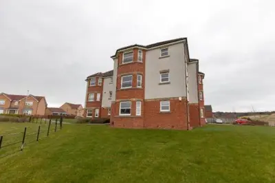 a large brick building in a field of grass at Super Prime Park View Duloch by TBA in Dunfermline