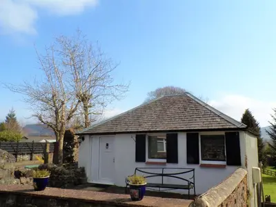 a white and black house with a fence at Groom's Cottage in Moffat