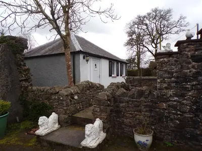 a house with a stone wall and two shoes at Groom's Cottage in Moffat