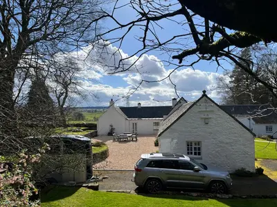 a car parked in front of a white house at South Craighall B&B in Eaglesham