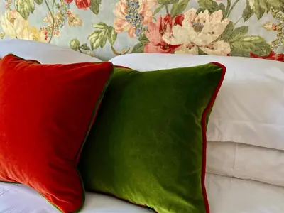 a red and green pillow sitting on a bed at South Craighall B&B in Eaglesham