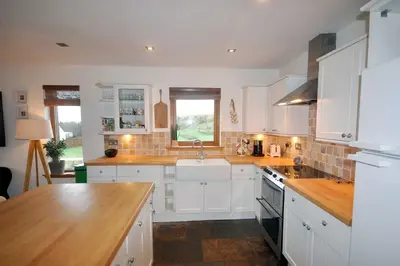 a kitchen with white cabinets and a sink at Portbahn, Bruichladdich in Bruichladdich