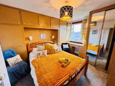 a bedroom with a large bed with a yellow bedspread at Park Road Holiday Home - Spacious 3 bedroom house with garden near Edinburgh in Rosyth