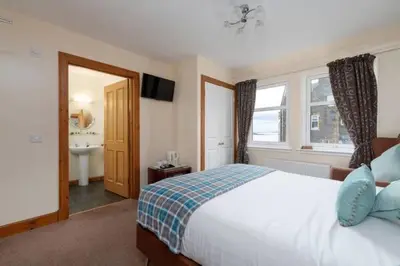 a bedroom with a bed and a bathroom with a sink at Kilchrenan House in Oban