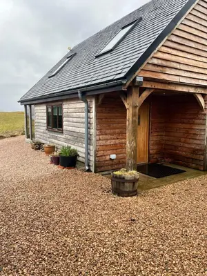 a wooden cabin with a gambrel roof and potted plants at Tigh a Chabar in Lochaline